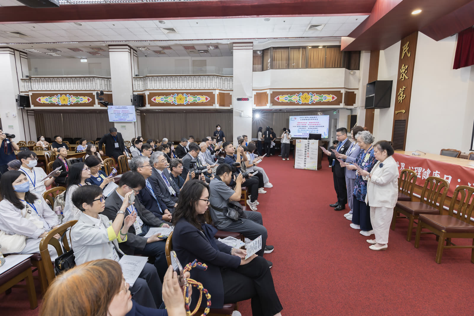 宣言發布現場，投影幕顯示心理健康城市共同宣言，台下與會者就座